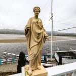 A stone statue on a wall in front of the Hotel Portmeirion