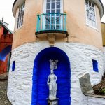 A curved building with a balcony and statue at Portmeirion Village