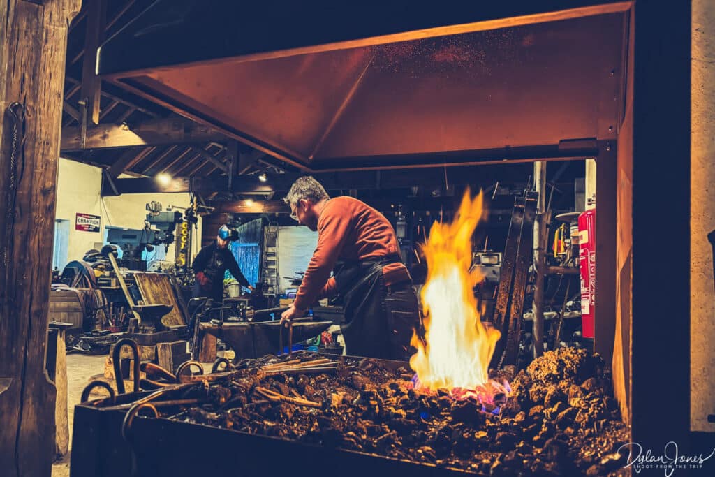 Pete working on the anvil behind the fire of the forge