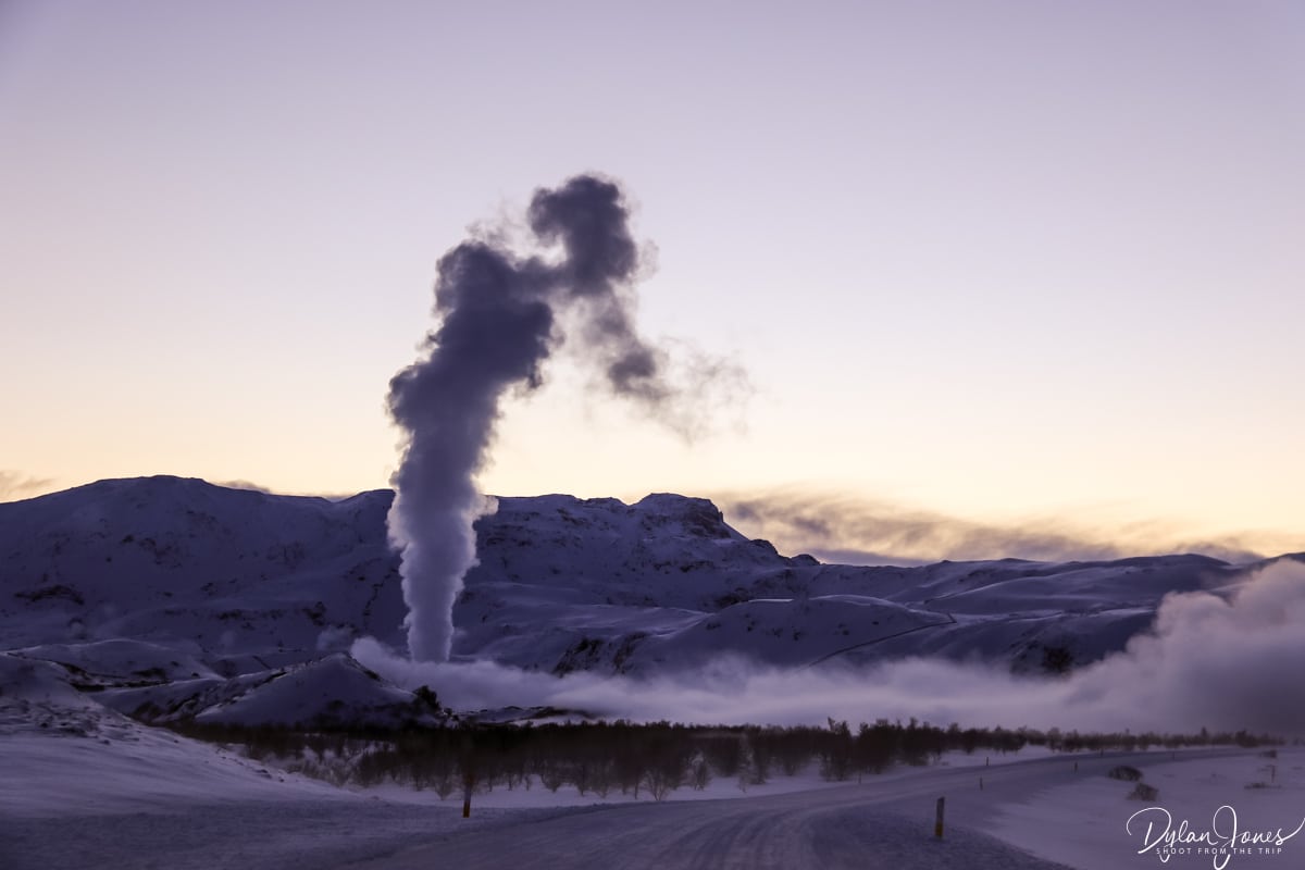 A snowy Icelandic landscape with steam rising from a geothermal power plant
